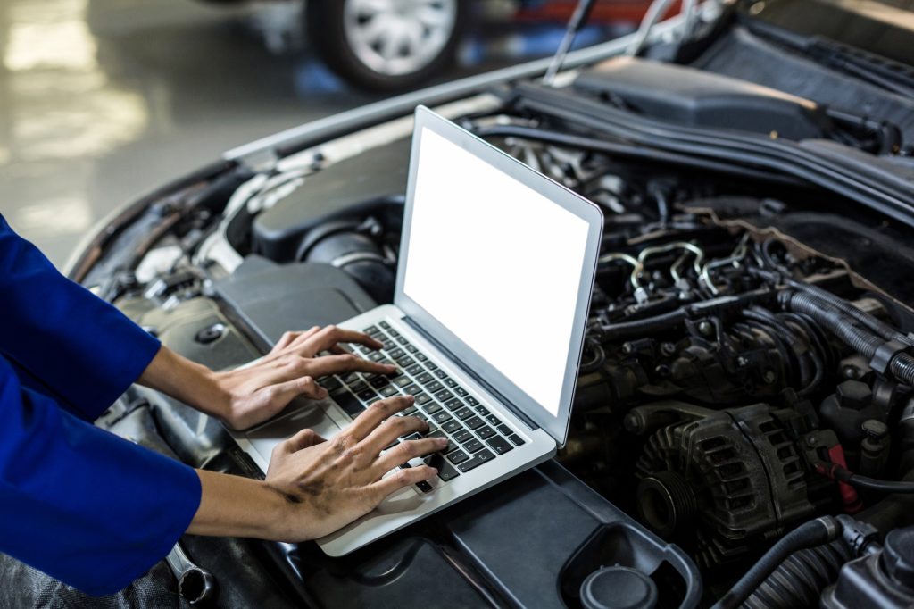Laptop connected to a car by a mechanic who is inspecting various error codes