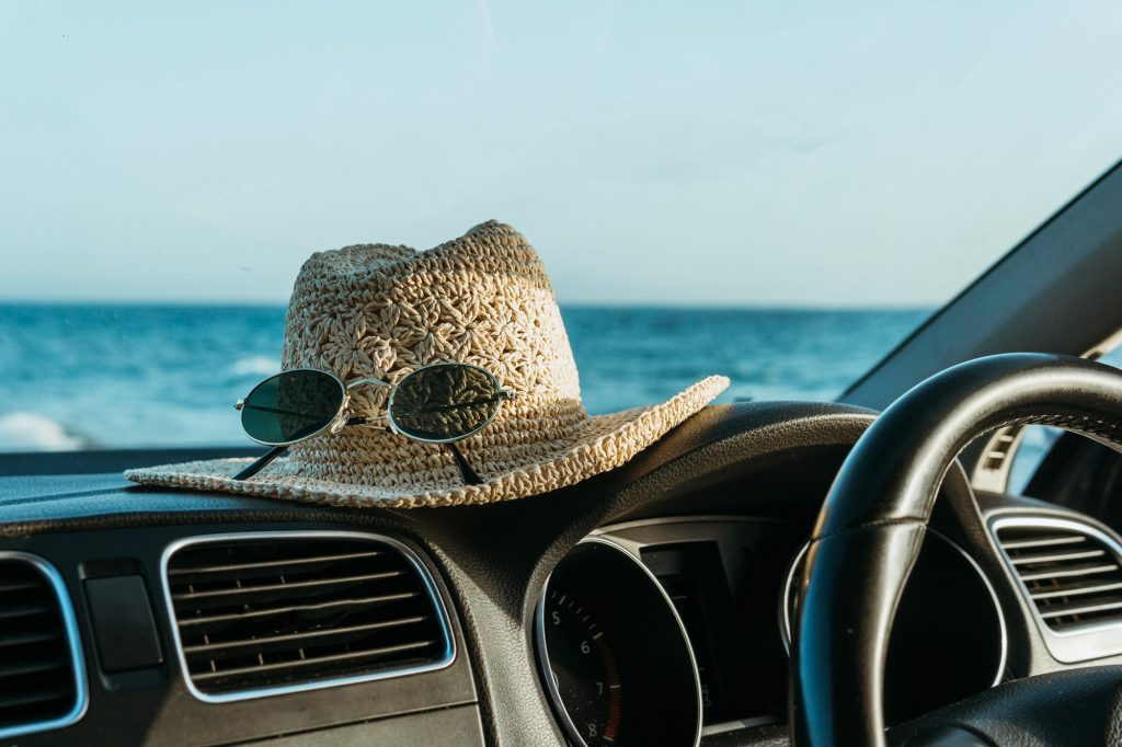 A Pair of sunglasses on a beach Hat on top of the dashboard